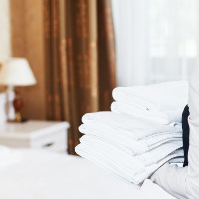 Hotel service. housekeeping maid with towels and bedclothes linen in room